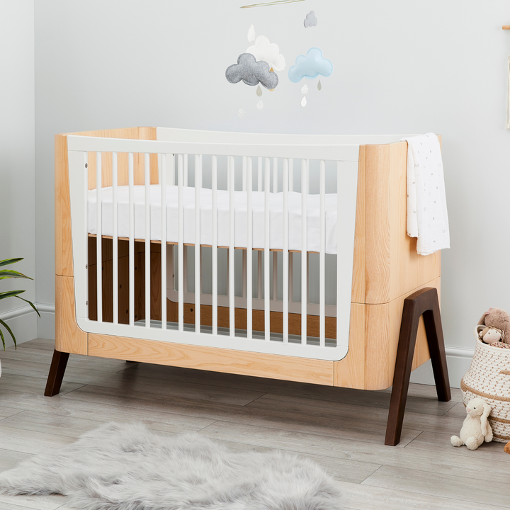 This image shows the stunning Hera Cot Bed in the Natural Ash and Walnut colour swatch