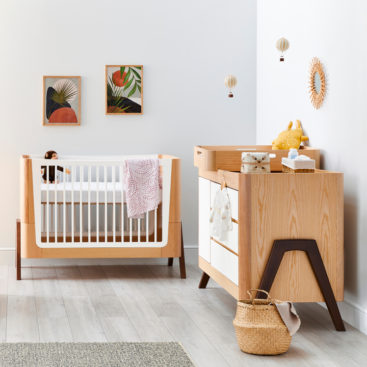 Gaia Baby Hera Cot Bed and Dresser in Ash and Walnut. A Solid wood dresser with three drawers and a side cabinet.