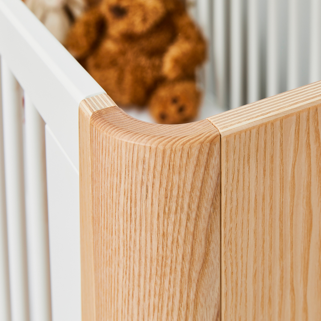 This image shows the stunning Hera Cot Bed in the Natural Ash and Walnut colour swatch