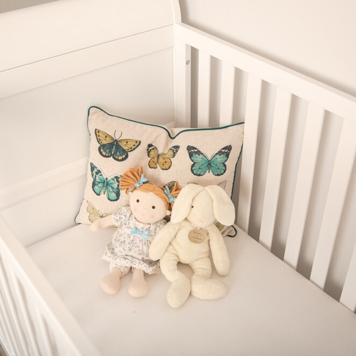 Gaia Baby Leto Cot Bed lifestyle image. White cot in a gender neutral nursery. Close up of doll and bunny in the cot